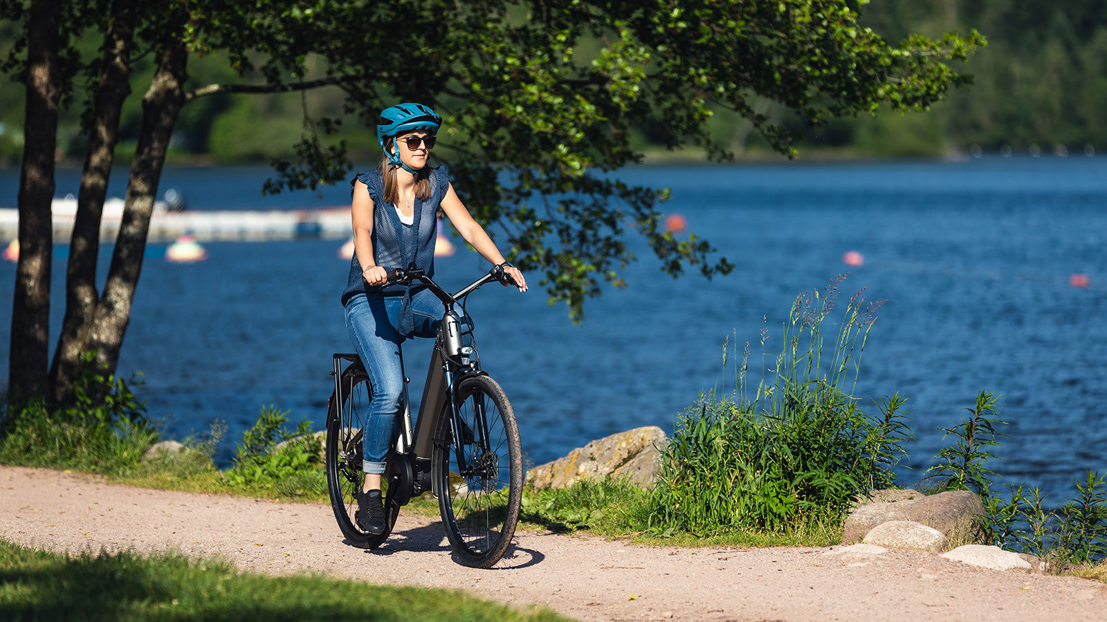 A woman riding a Moustache electric bike next to a lake.