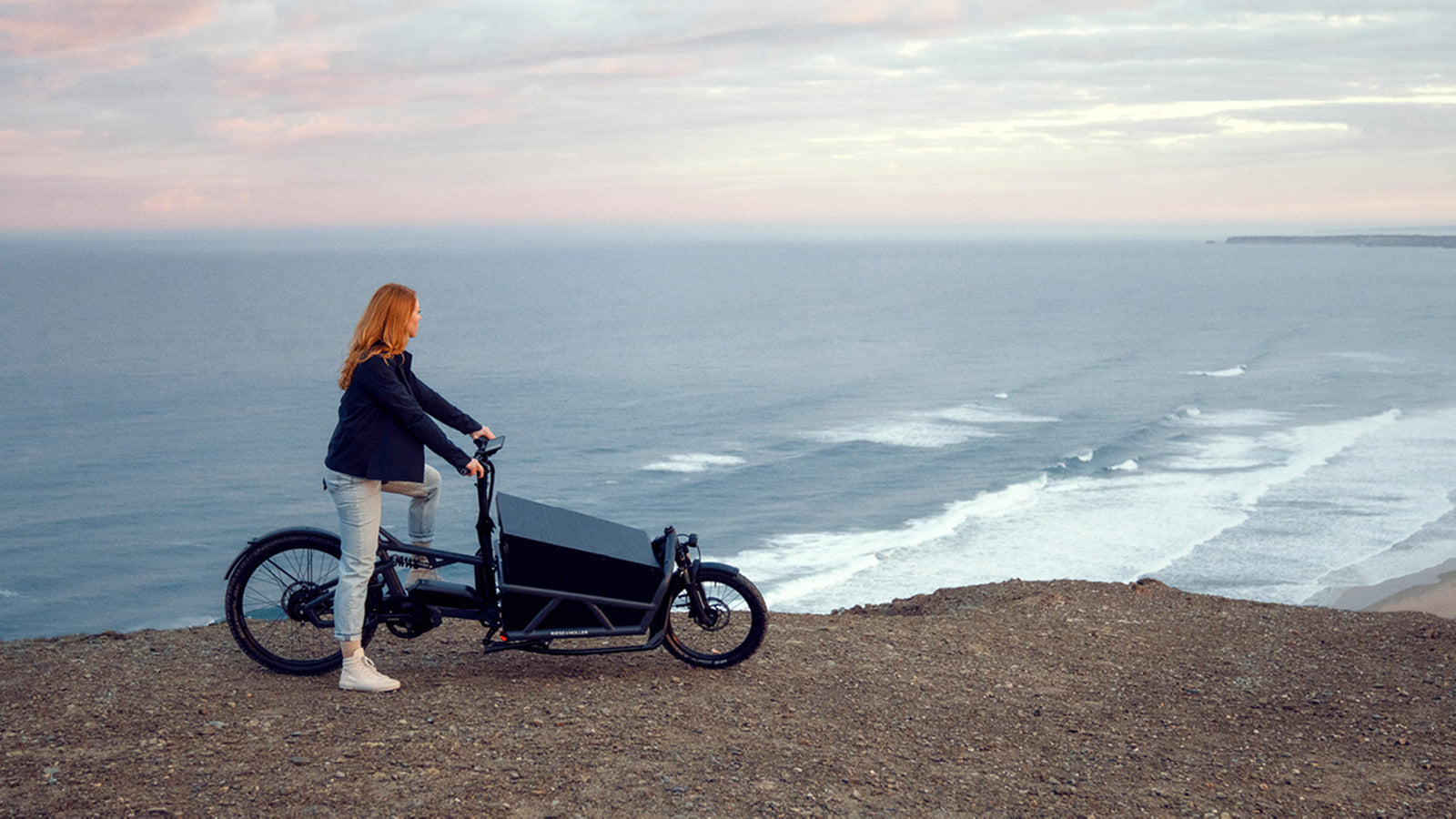 A woman on a Riese and Muller electric cargo bike looking out to sea